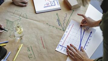 Une table avec des plans d’architecture, un carnet et un verre contenant des rondelles de citron.