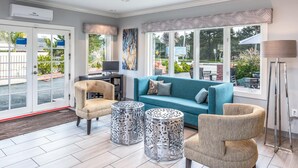 A modern living room with a blue sofa, beige armchairs, and patterned ottomans.