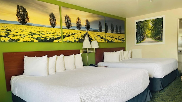 A hotel room with two beds, a green wall, and a large landscape painting. - Days Inn by Wyndham Westley (Westley)