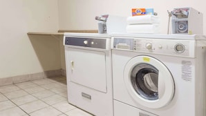 A front-loading washing machine and dryer side by side in a laundry room with a tiled floor. - Days Inn by Wyndham Westley (Westley)