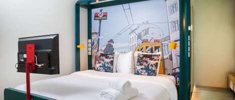 Habitación de hotel con cama, televisor montado en la pared y ventana con vistas a edificios.