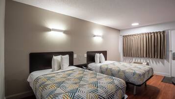 Habitación de hotel con dos camas, una lámpara en el techo, una ventana con cortinas y un termostato en la pared.
