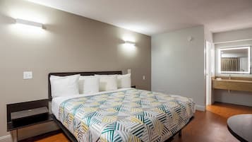 A bedroom with a bed, bedside table, and a bathroom with a mirror.