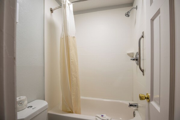 A bathroom with a toilet, a shower curtain, a bathtub, and a door with a golden handle. - Motel 6 Richmond, VA - Midlothian Turnpike (Richmond)