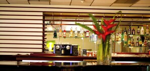 Zona de bar amb calaixos plens de garrafes de licors, una màquina de cafè i una planta decorativa.