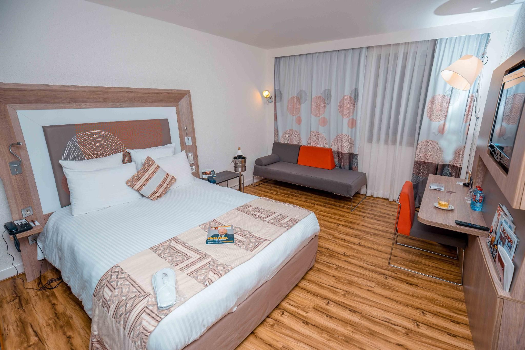 Habitación de hotel con una cama grande, un sofá, un escritorio con silla y un minibar.