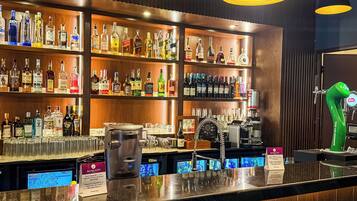 A bar area with shelves of liquor bottles, a coffee machine, and a digital screen displaying a map.