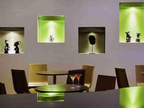 Comedor con una mesa redonda, sillas y un panel iluminado en verde.