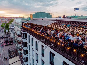 Eine Dachterrasse mit Sitzgelegenheiten im Freien und Blick auf die Stadt.