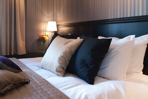 Ein ordentlich bezogenes Bett mit verschiedenen Kissen und einer Nachttischlampe.