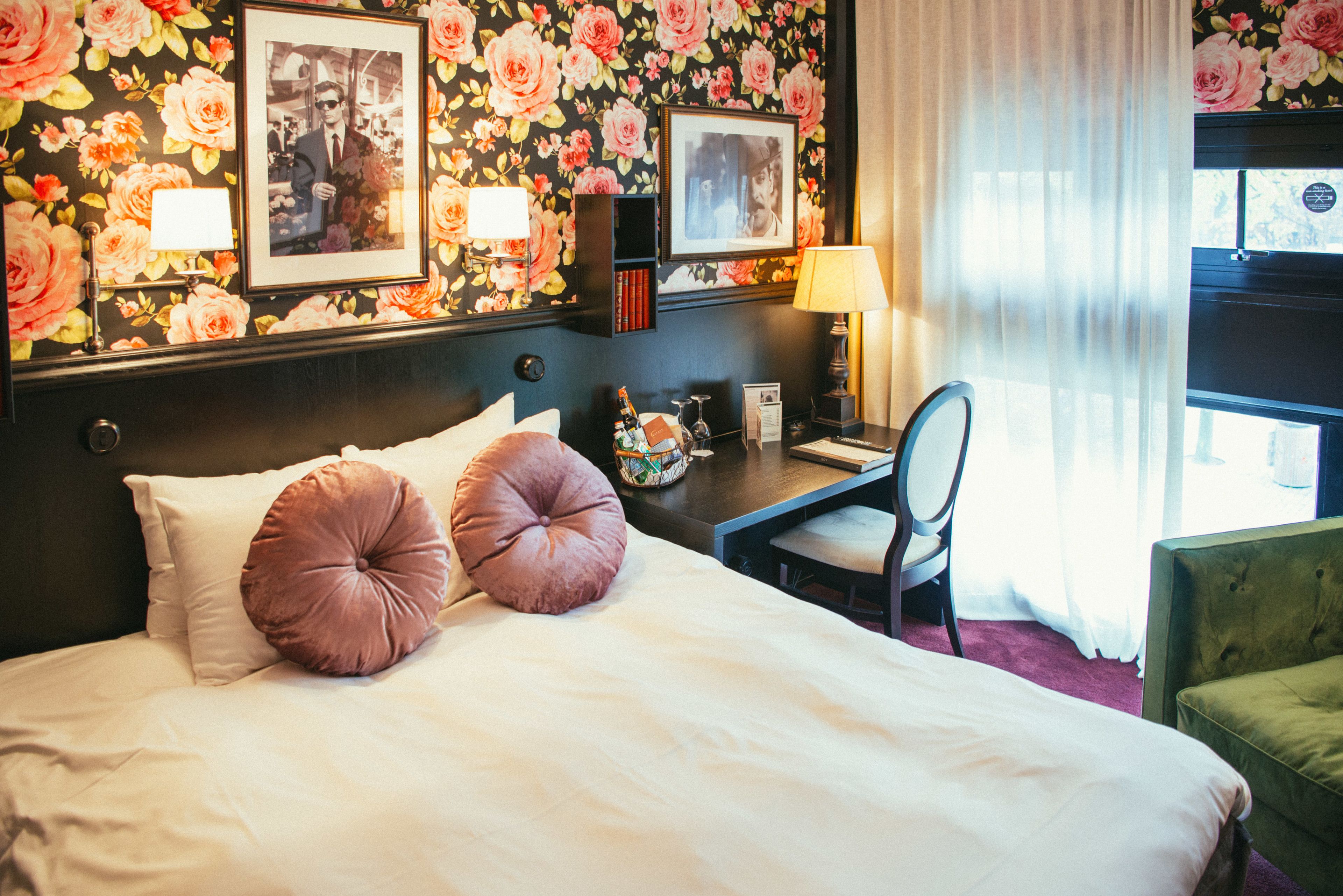 A hotel room with a bed, a desk, a chair, and a window with curtains.