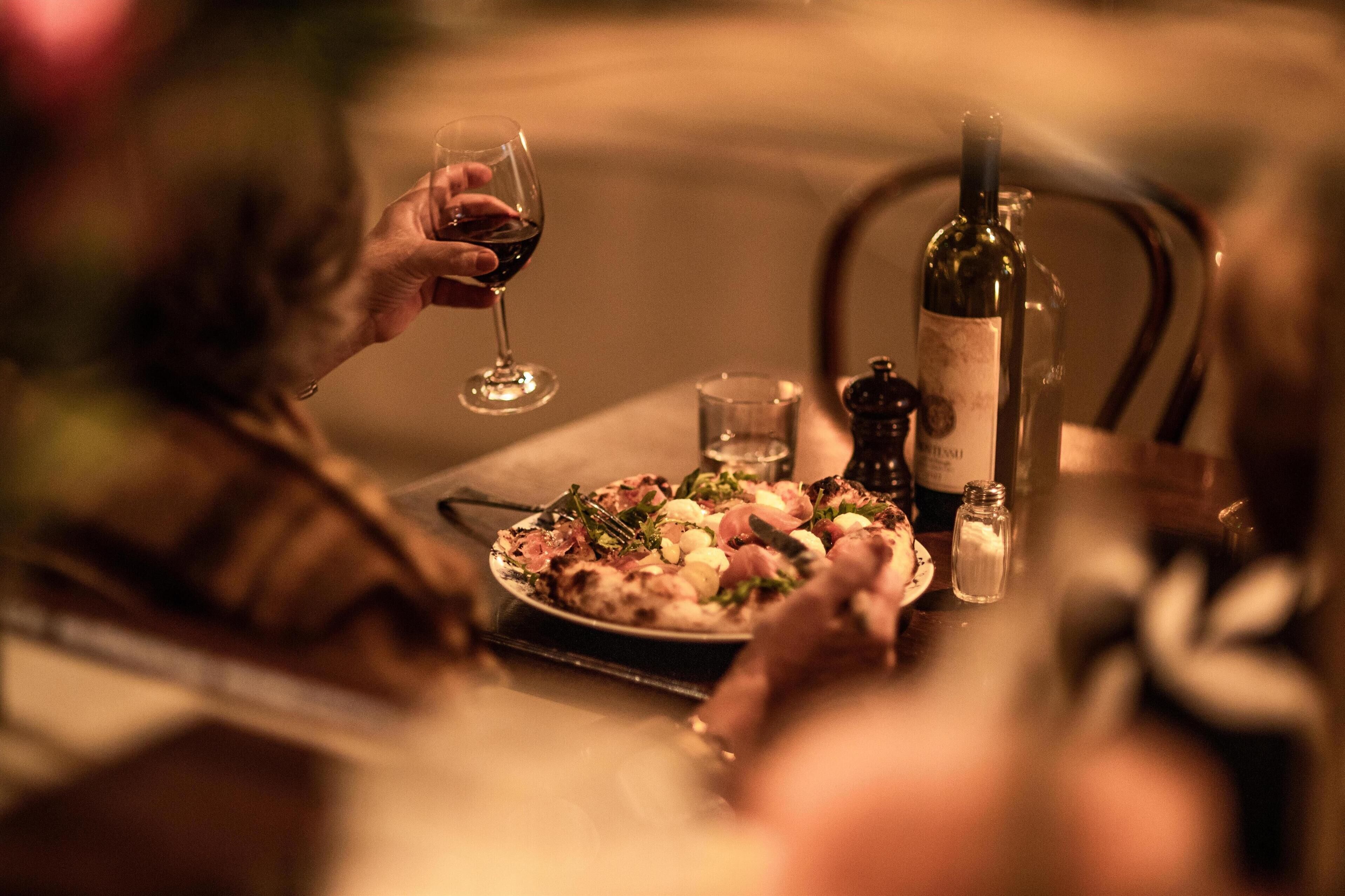 Una mesa de comedor con un plato de comida, una botella de vino y un salero.