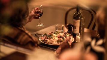 Una mesa de comedor con un plato de comida, una botella de vino y un salero.