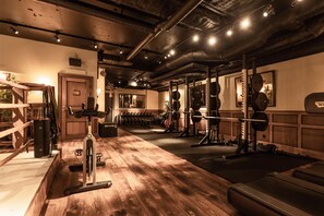 Ett gym med trägolv, utrustning för styrketräning och en spegel på väggen.