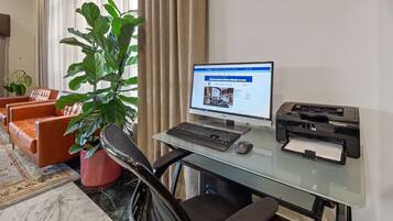 A home office setup with a computer, printer, and a large green plant.