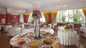 A dining area with round tables covered in white tablecloths, surrounded by chairs. - Hotel Milton (Rimini)