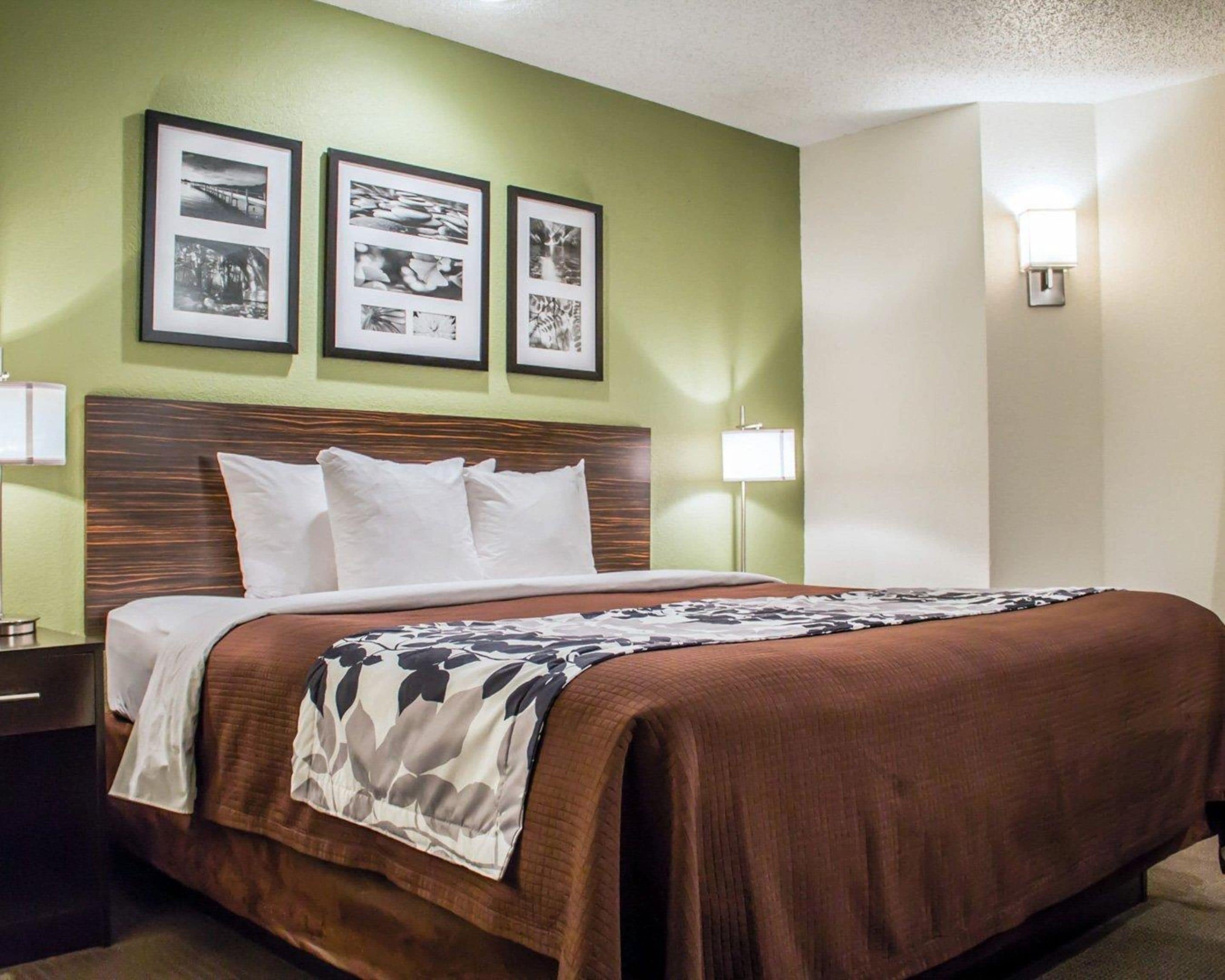 A hotel room with a bed, green walls, and three framed pictures on the wall.