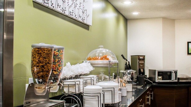 A buffet setup with various food items and condiments, a microwave, and a coffee machine. - Sleep Inn Summersville - New River Gorge Area (Summersville)