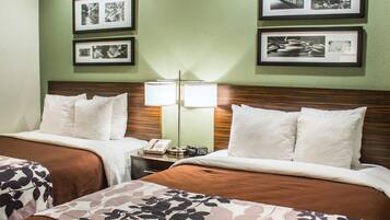 A hotel room with two beds, a nightstand with a lamp, and framed pictures on the wall.