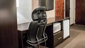 A compact hotel room with a kitchenette, a flat-screen TV mounted on the wall, a wooden door, and a small refrigerator. - Sleep Inn Summersville - New River Gorge Area (Summersville)