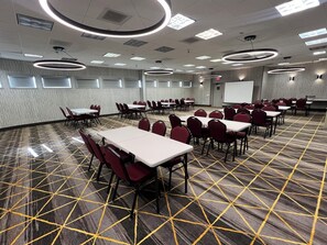 A conference room with tables and chairs, a projector screen, and a patterned carpet. - Holiday Inn Rancho Cordova by IHG (Rancho Cordova)