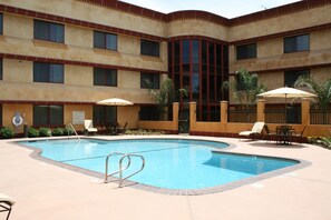 A hotel with a swimming pool, outdoor seating, and a courtyard.
