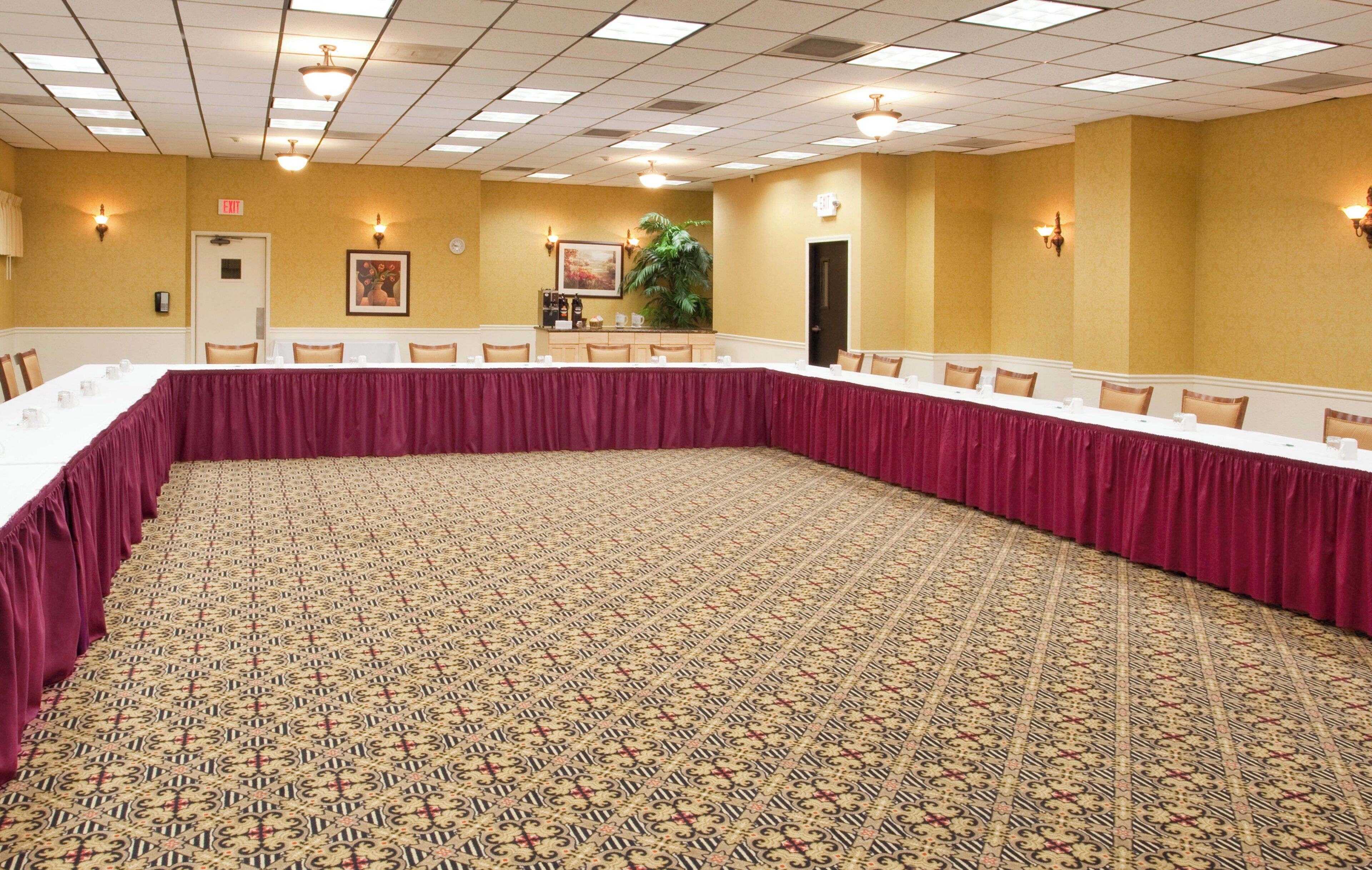 A conference room with a patterned carpet, a long table with chairs, and a door marked 'EXIT'.