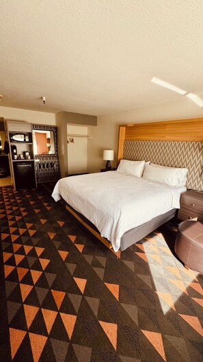 A hotel room with a bed, a desk, a chair, a small table, and a mirror. - Holiday Inn Rancho Cordova by IHG (Rancho Cordova)