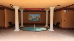 A pool area with columns, a painting, and a chair.