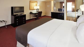 Une chambre d’hôtel comprenant un lit, un bureau avec une chaise, une télévision, un four à micro-ondes et un petit réfrigérateur.