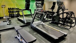 A gym with treadmills, a bench, and dumbbells.