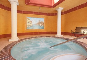 Un jacuzzi con un cuadro de una escena de canal en la pared, columnas blancas y un banco.