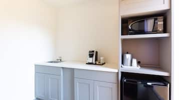 Et lille køkken med vask, kaffemaskine, mikrobølgeovn og køleskab.