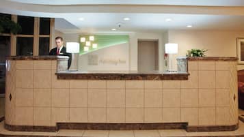 A reception desk with a nameplate, a plant, and a lamp.