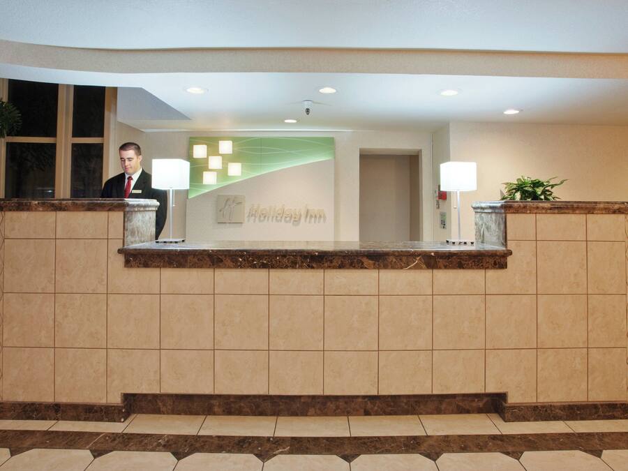 A reception desk with a nameplate, a plant, and a lamp.
