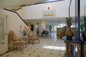 Un hall de hotel con mostrador de recepción, zona de estar y una escalera.