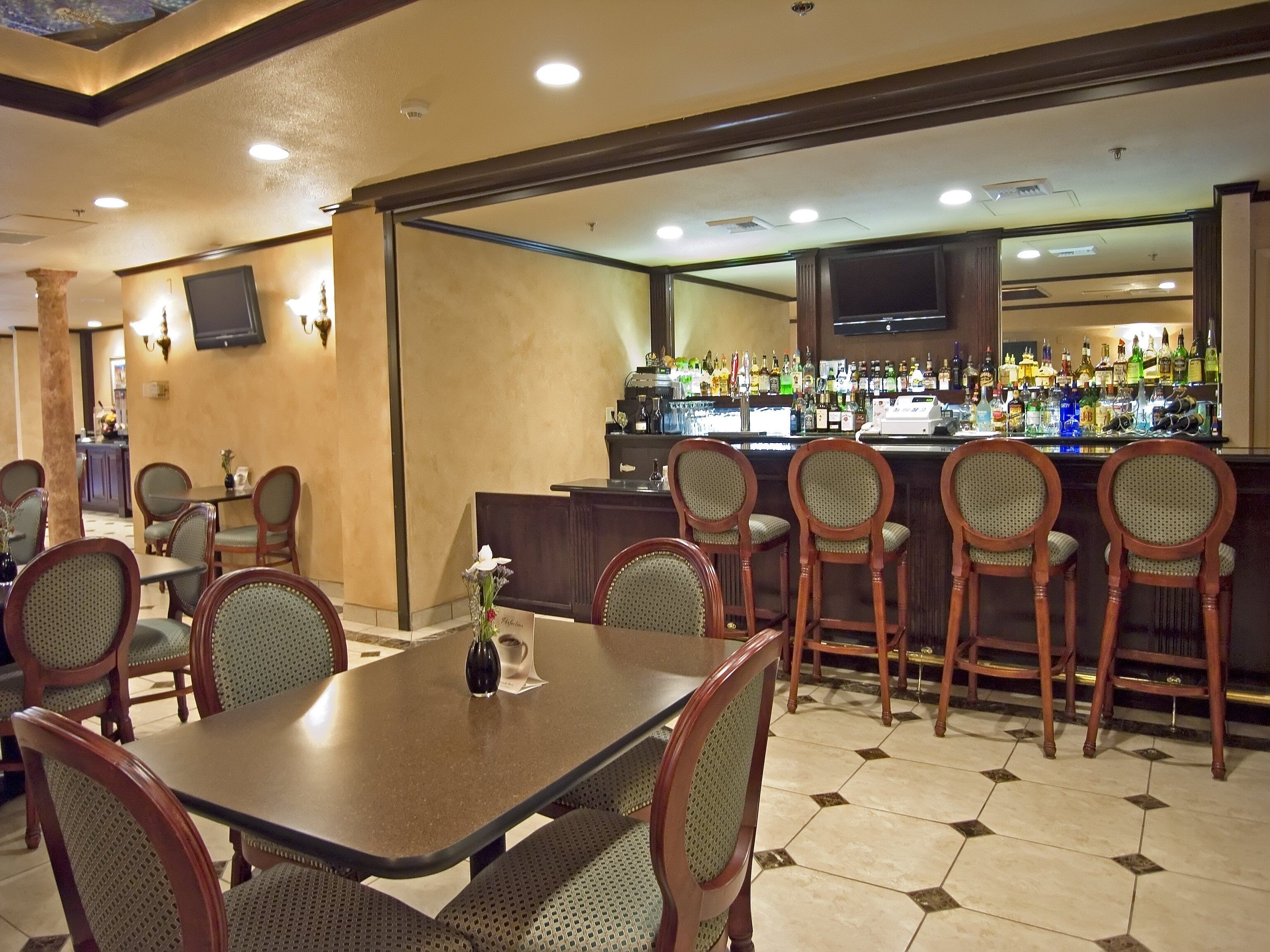 A restaurant with a bar area, multiple tables, and chairs.