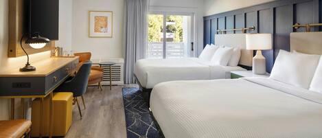 A hotel room with two beds, a desk with a chair, a TV, and a large window with a view of greenery.