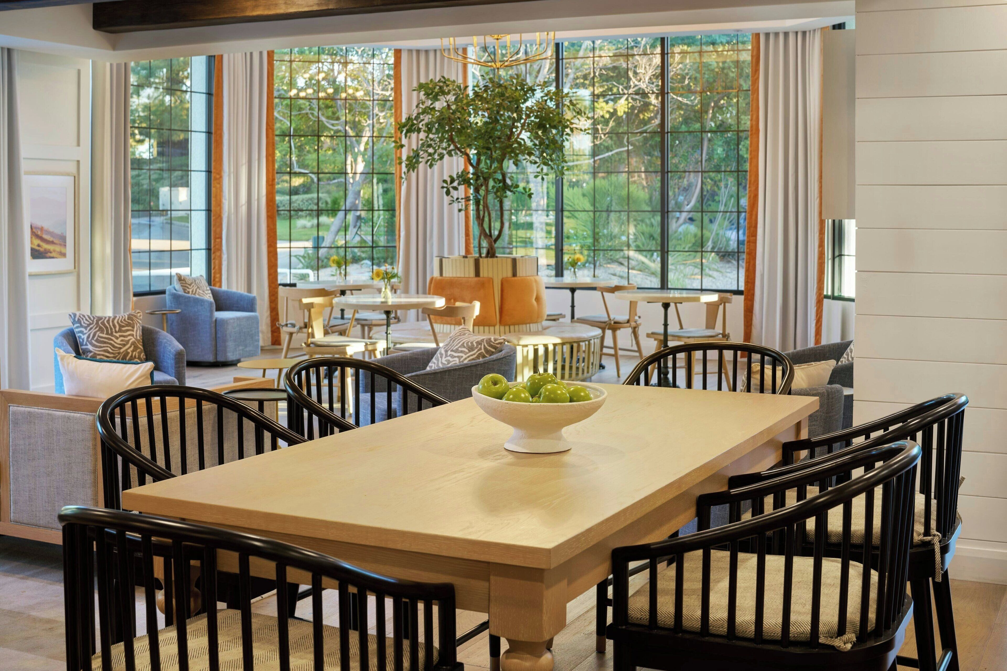 A dining area with a wooden table, black chairs, and a bowl of green apples.
