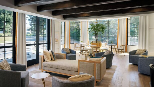A spacious living room with large windows, a central coffee table, and multiple seating options including sofas and armchairs. - Tiller House, Laguna Hills, A Tribute Portfolio Hotel (Laguna Hills)