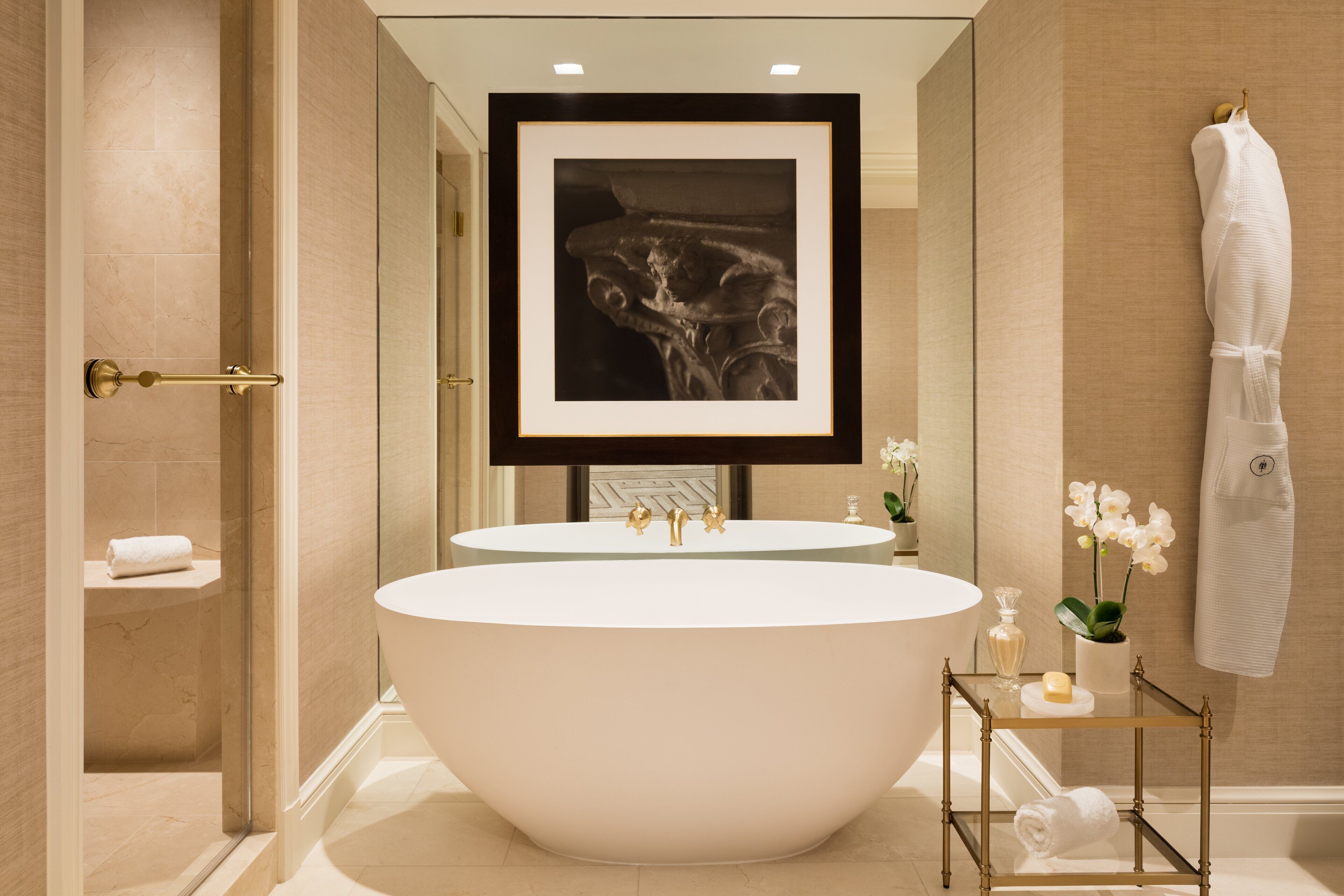 Un baño moderno con una bañera independiente, dos lavamanos y una obra de arte enmarcada sobre los lavamanos.