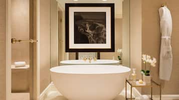 Un baño moderno con una bañera independiente, dos lavamanos y una obra de arte enmarcada sobre los lavamanos.