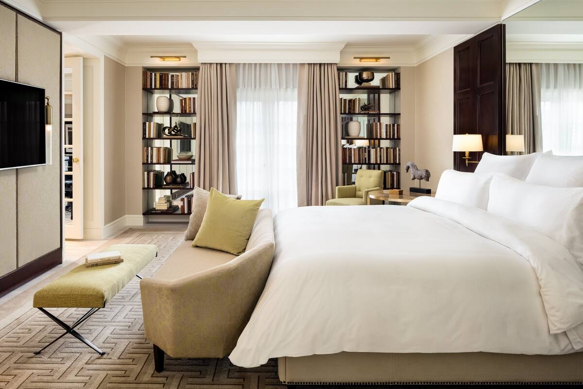 Une chambre d’hôtel avec un grand lit, un canapé, une petite table, une bibliothèque et un téléviseur.