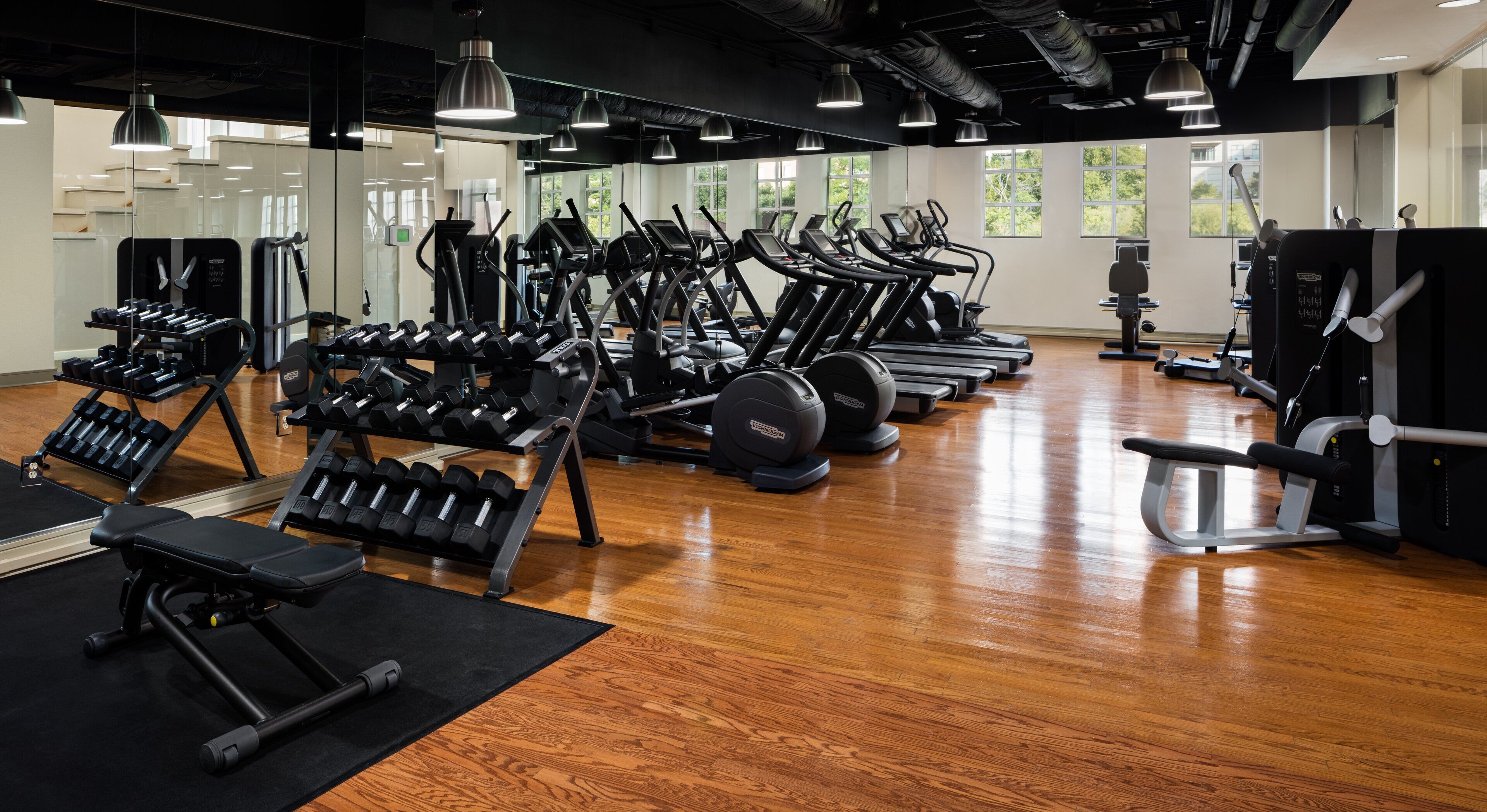Ein Fitnessstudio mit Laufbändern, Crosstrainern und Gewichtsbänken.