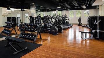 Ein Fitnessstudio mit Laufbändern, Crosstrainern und Gewichtsbänken.