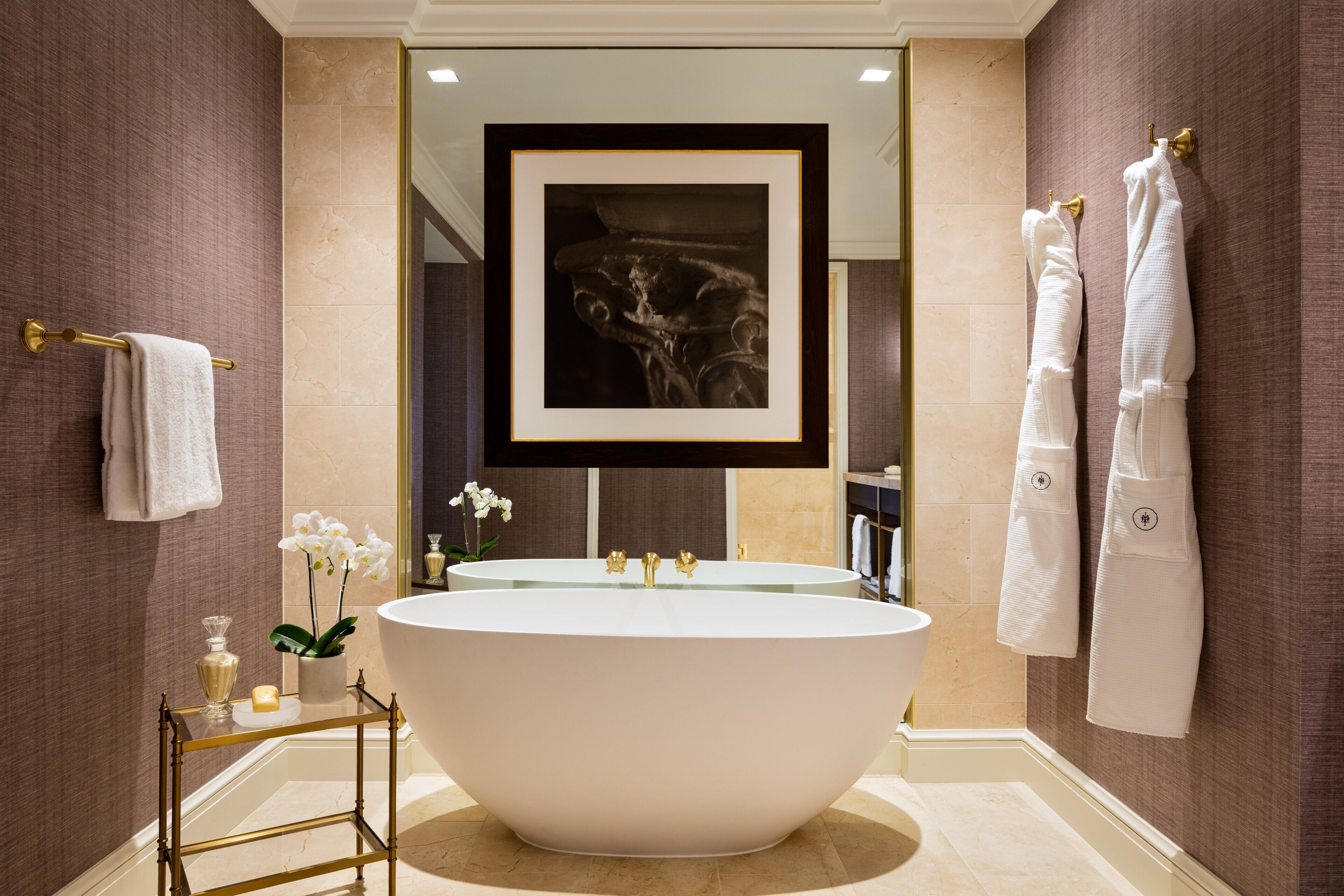 Une salle de bain moderne avec une baignoire sur pieds, un grand miroir et une œuvre d’art encadrée placée au-dessus du miroir.