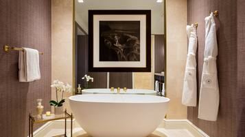 Une salle de bain moderne avec une baignoire sur pieds, un grand miroir et une œuvre d’art encadrée placée au-dessus du miroir.