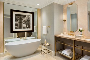 Bathroom features a bathtub, large mirror, and framed artwork.