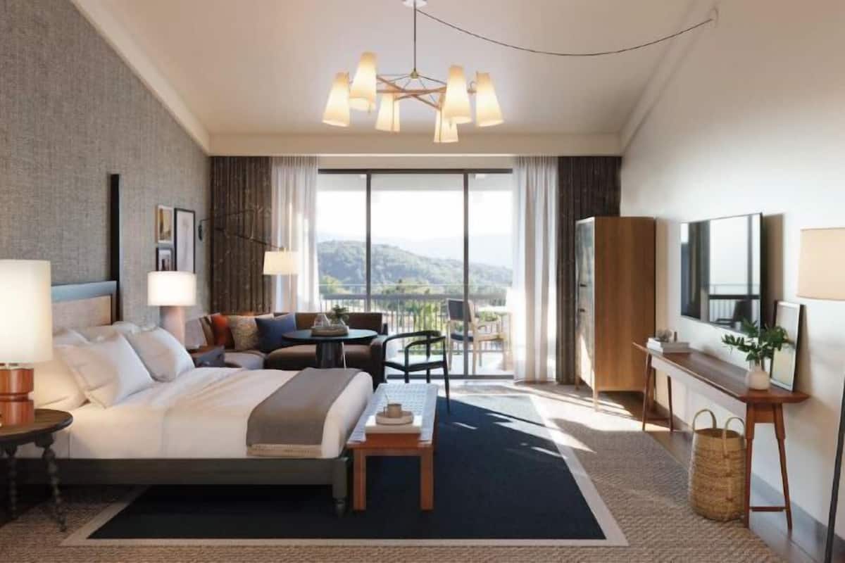 Une chambre d’hôtel avec un grand lit, un bureau, une chaise, une télévision et une vue sur l’extérieur.
