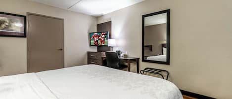Une chambre d’hôtel équipée d’un lit, d’un bureau, d’une chaise, d’une télévision et d’un miroir.